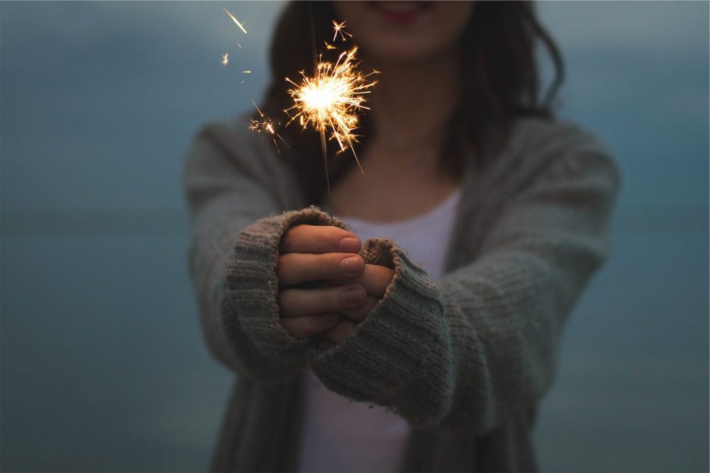 woman holding sparkler on the beach